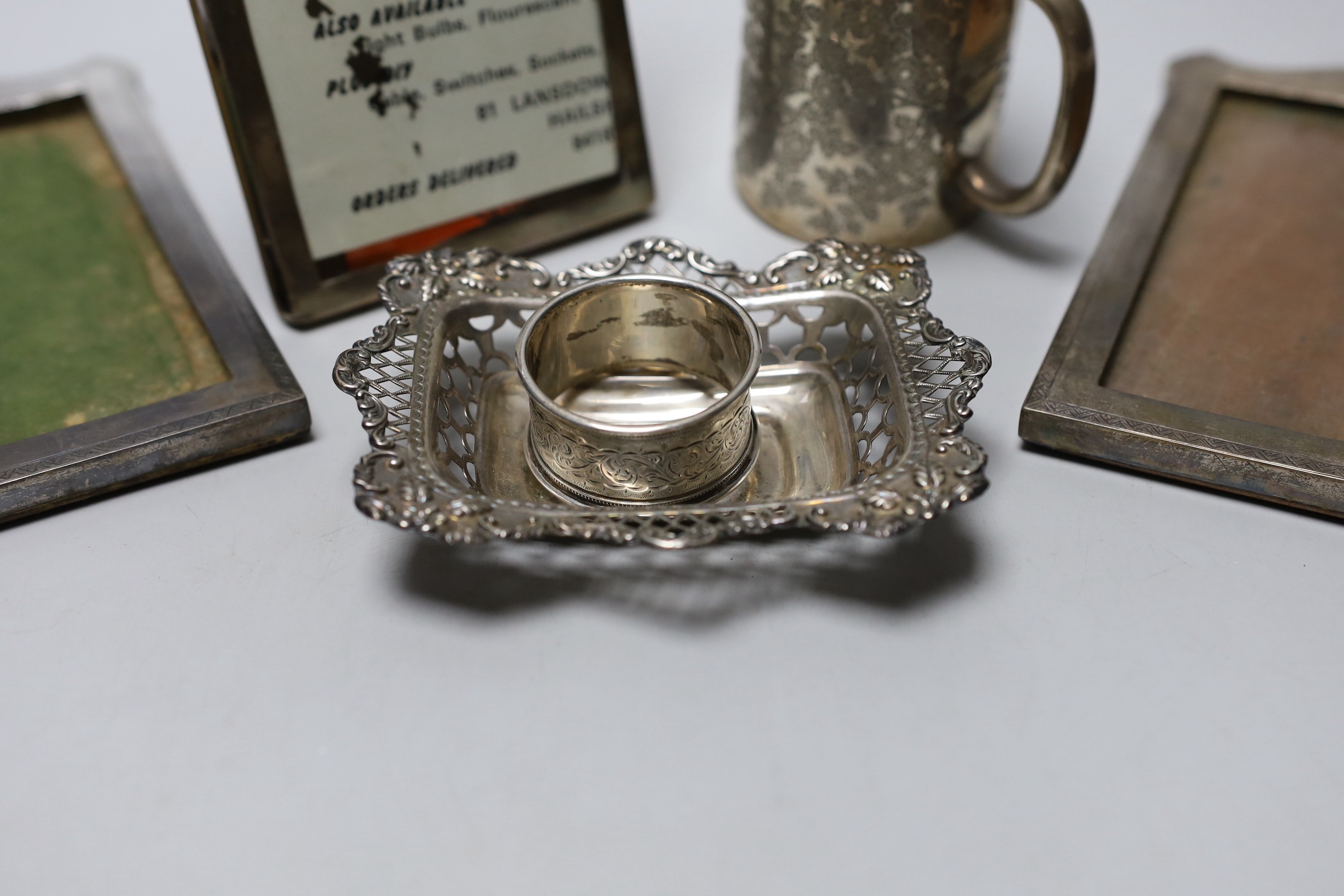 A Victorian engraved silver christening mug, London, 1890, 81mm, a silver napkin ring, a repousse silver dish and three silver mounted photograph frames.